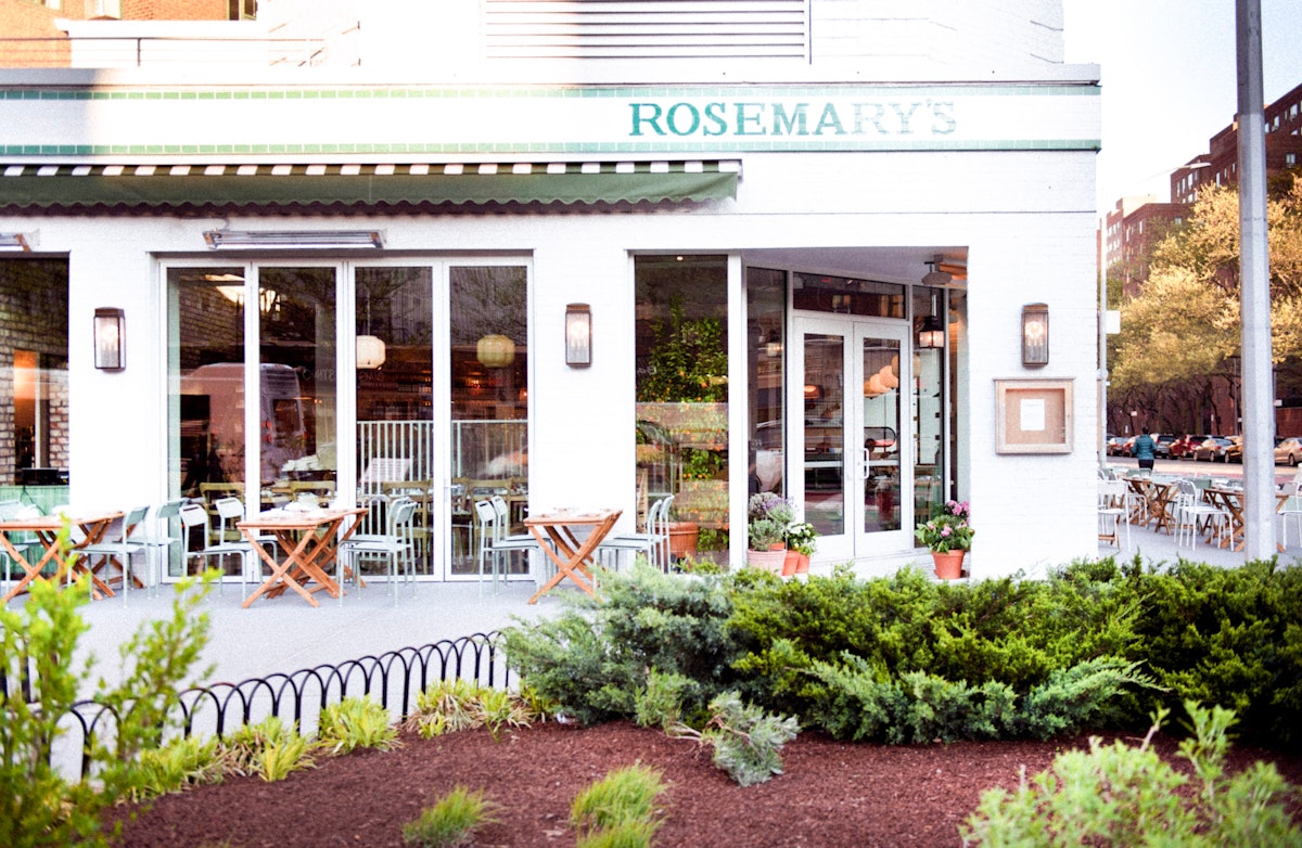 An exterior view of Rosemary's East with lush garden beds in front of the restaurant.