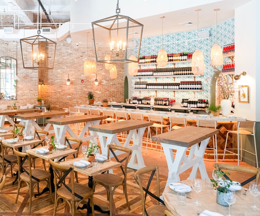 Large standing wine bar tables at Rosemary's Midtown with the full bar in the background.